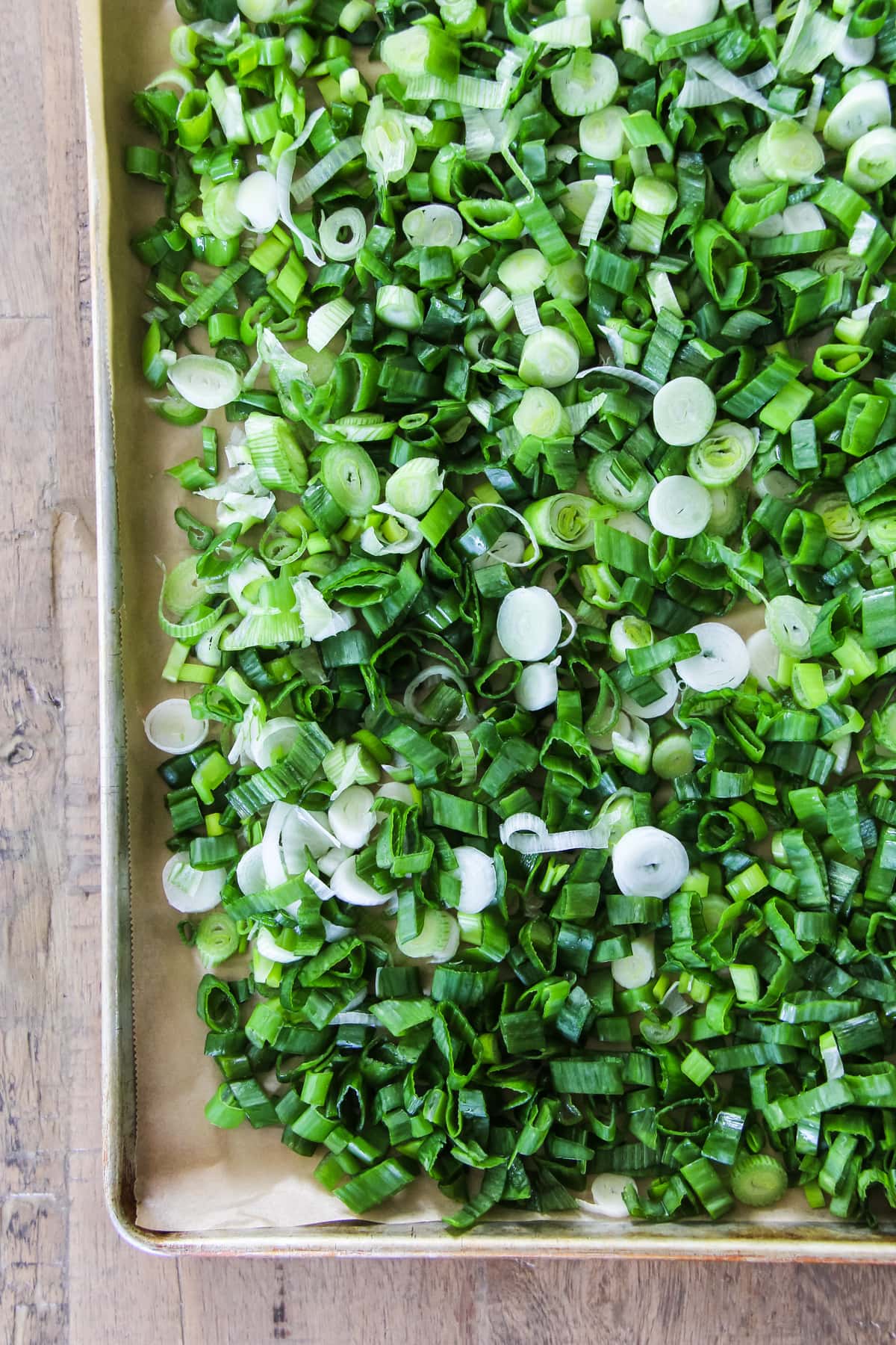 a top down image of a baking sheet full of green onions ready to go into the freezer