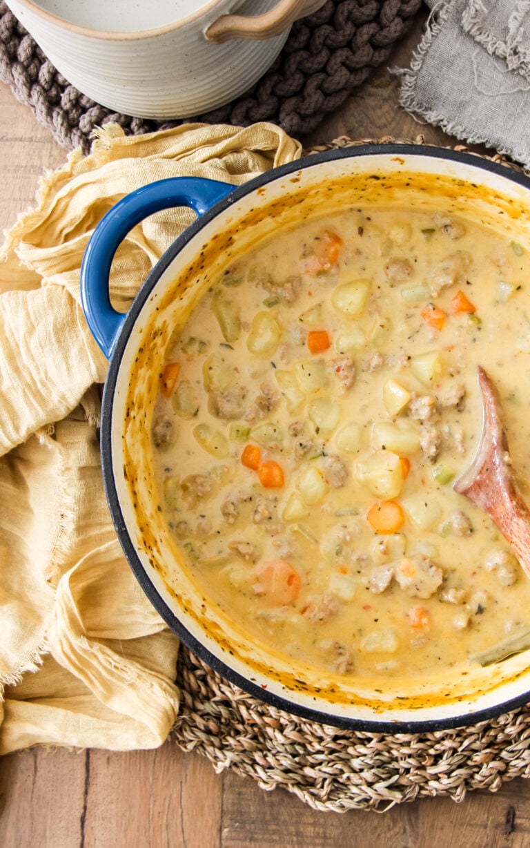 a top down close up image of a pot of sausage potato soup