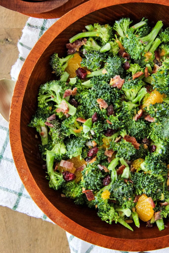 a top down image of a wooden bowl filled with broccoli salad
