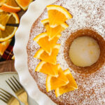 a close up of an orange bundt cake with fresh orange slice garnishes