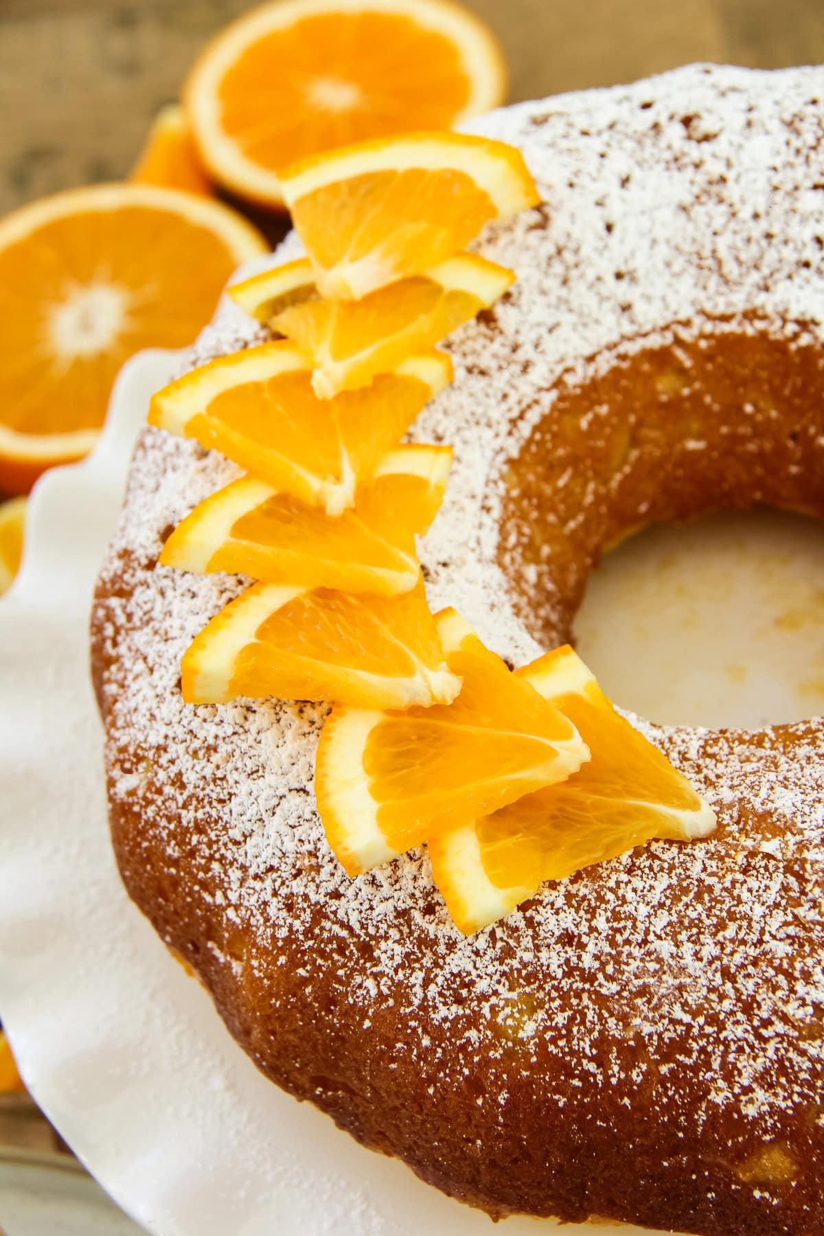 a close up of an orange bundt cake with fresh orange slice garnishes