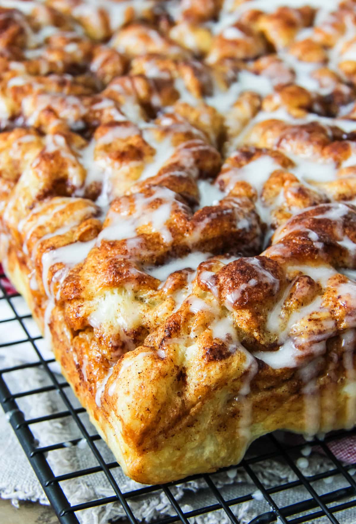 cinnamon roll focaccia with sugar glaze drizzle sitting on a wire cooling rack