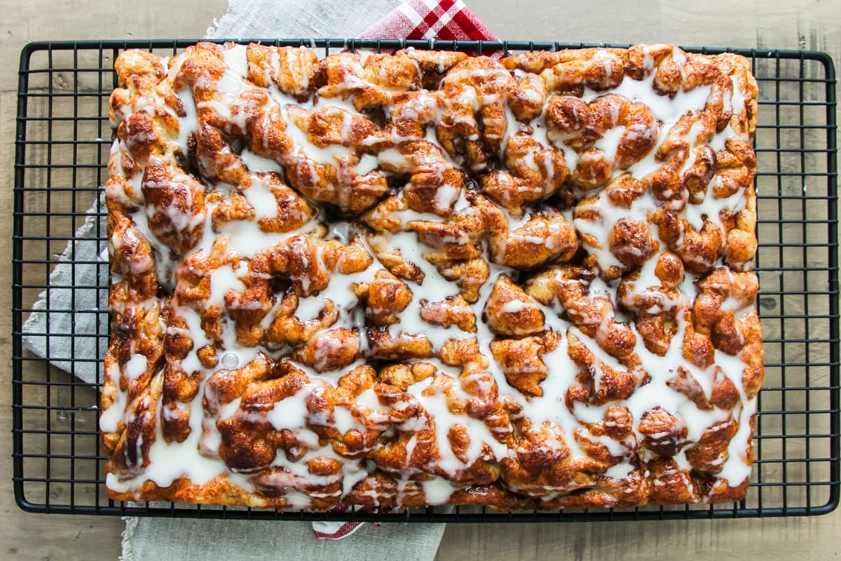 cinnamon roll focaccia with sugar glaze drizzle sitting on a wire cooling rack