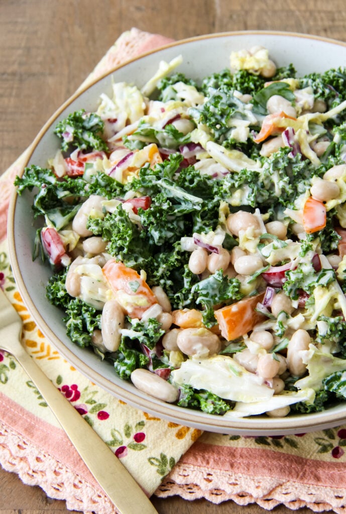 a bowl of Kale and White Bean Salad on a wood table