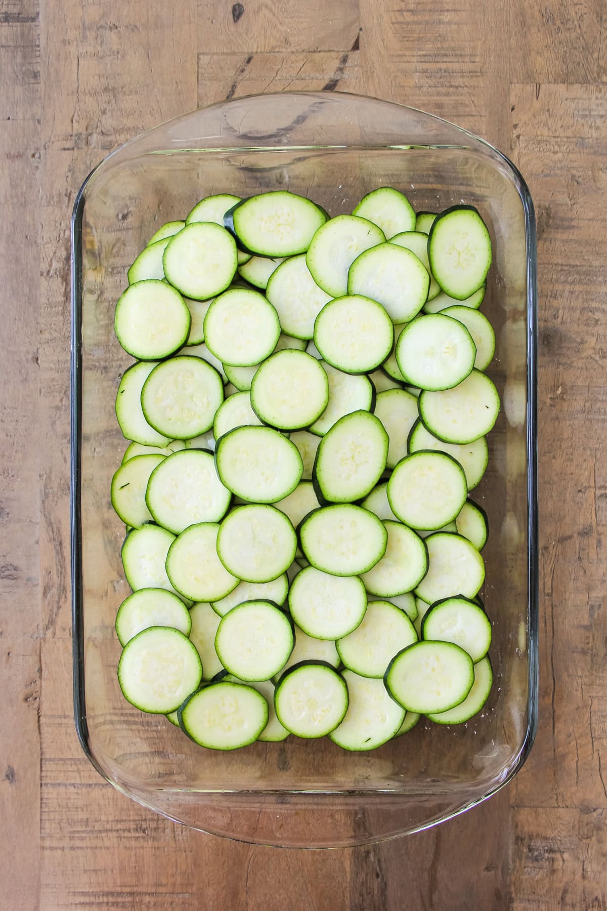 a top down image of a baking pan of unbaked crustless zucchini pie