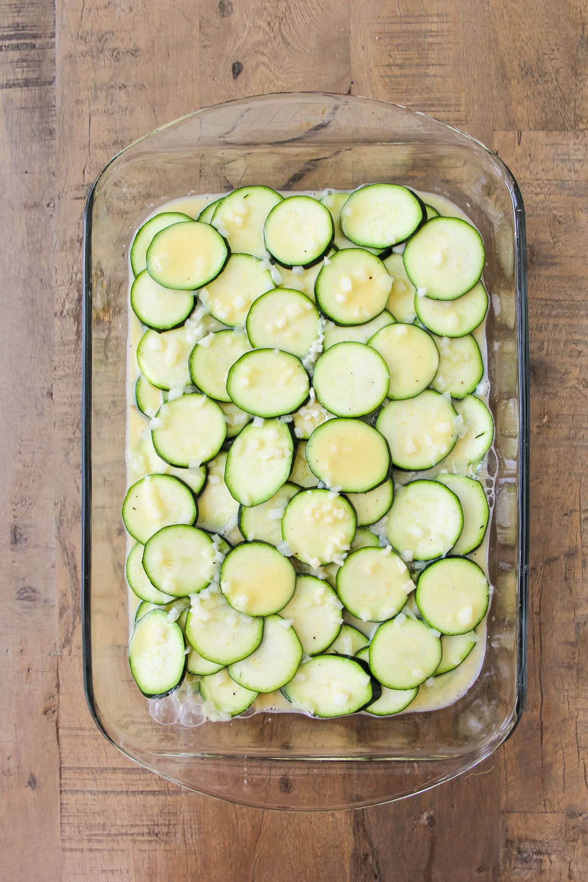 a top down image of a baking pan of unbaked crustless zucchini pie