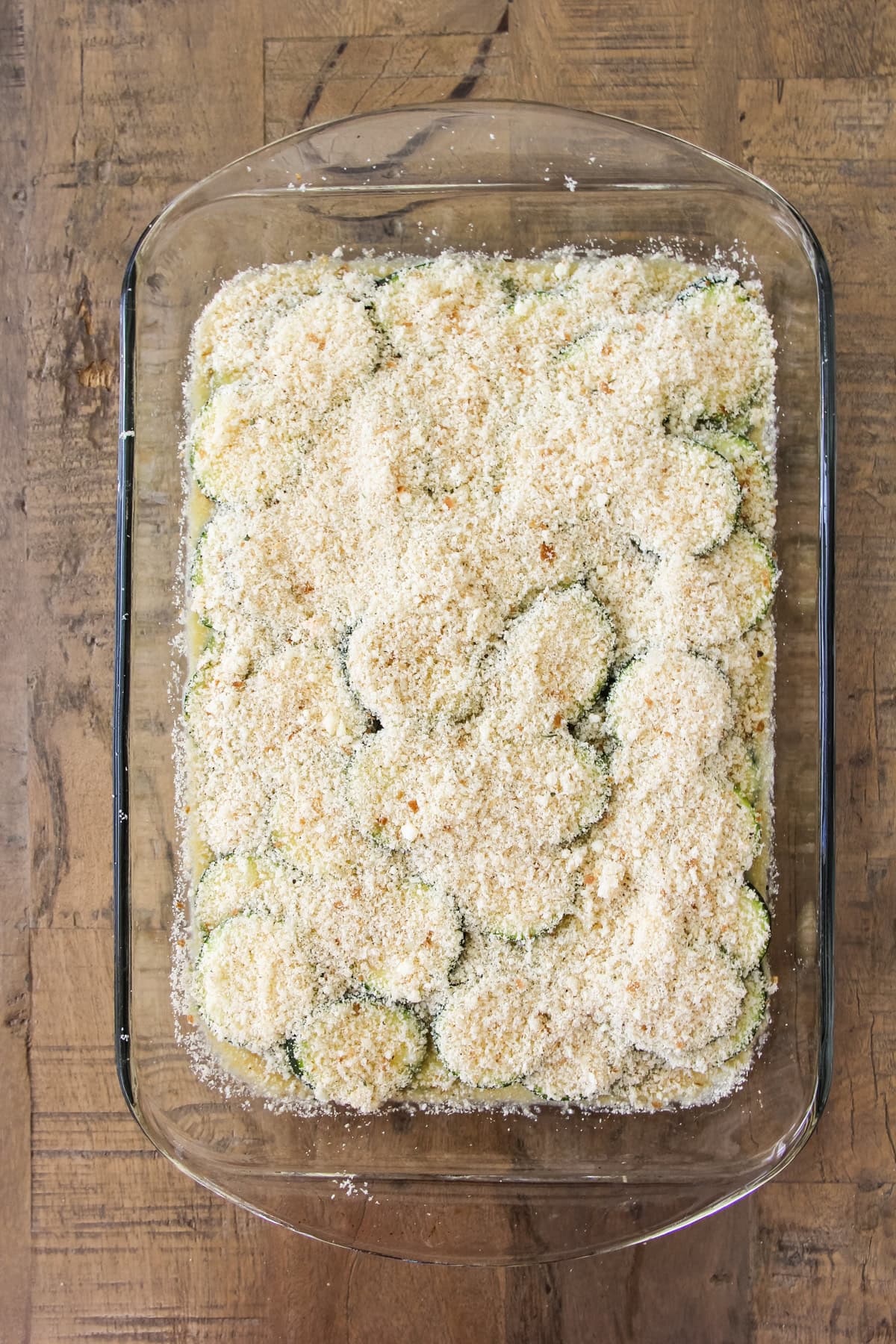 a top down image of a baking pan of unbaked crustless zucchini pie