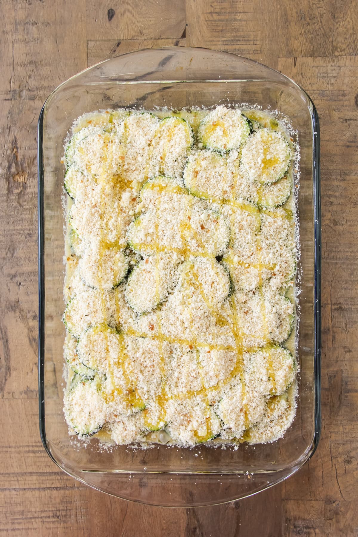 a top down image of a baking pan of unbaked crustless zucchini pie