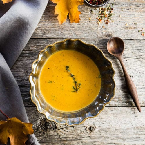 a bowl of roasted squash soup on a wooden table