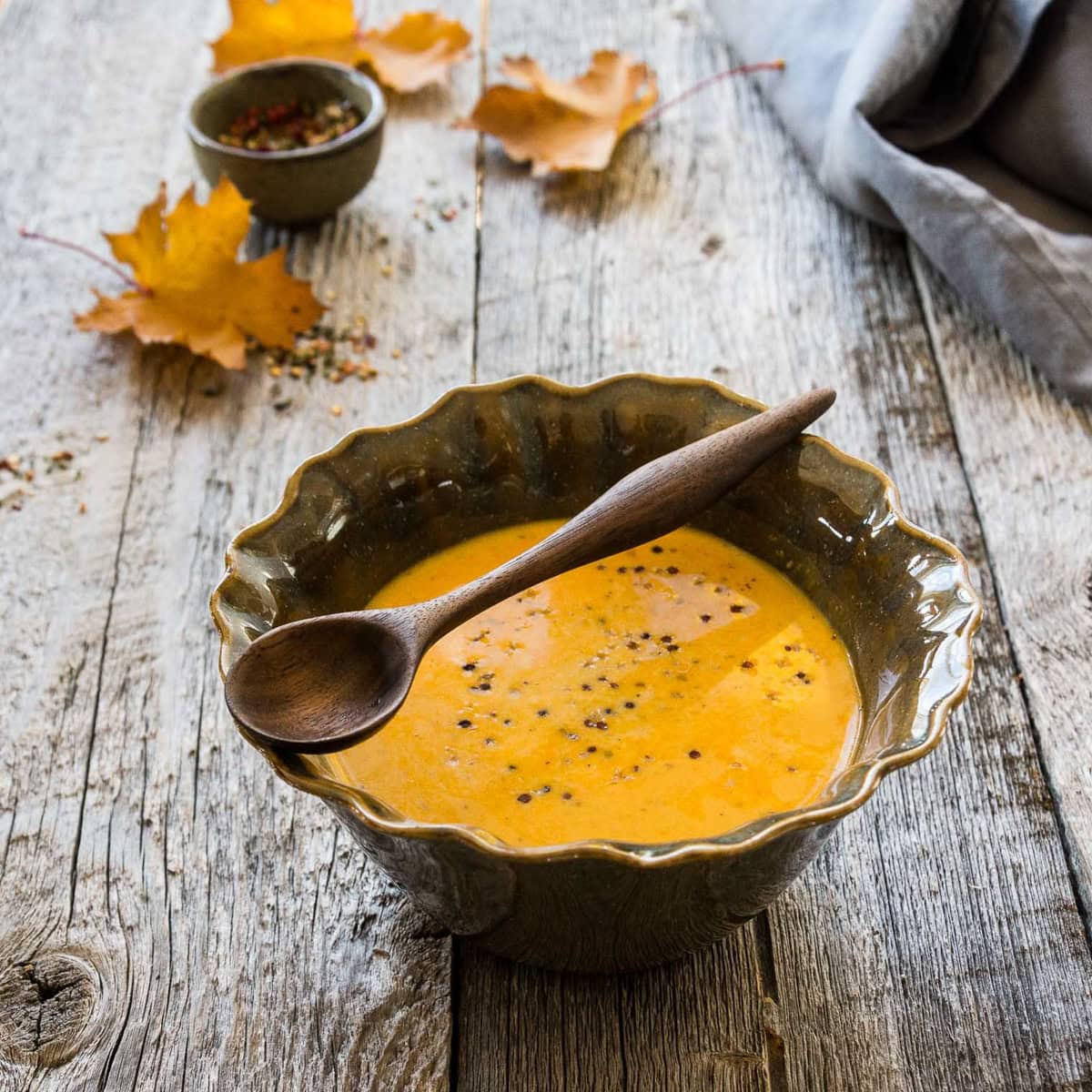 a bowl of roasted squash soup on a wooden table